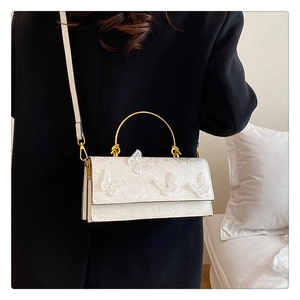 Close-up of white butterfly lace embroidery and gold metal handle on elegant lady's bag