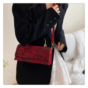 Detailed embroidery of black butterflies on a vintage red lace handbag with gold handles