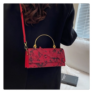 Détail du sac rouge avec des appliques papillons 3D et une poignée en métal doré