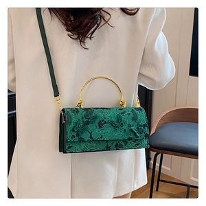Close-up of green lace handbag with floral butterfly embroidery and gold metal handle
