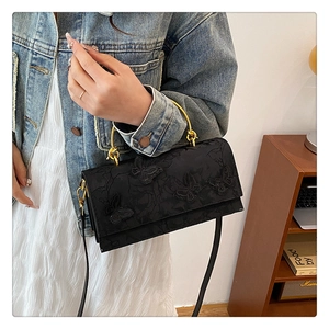 Close-up of black crossbody bag featuring detailed 3D butterfly embroidery and gold handle