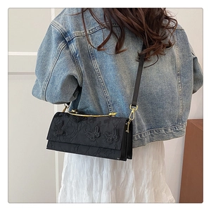 Détail du sac bandoulière noir avec broderie papillon 3D et poignée métallique chic