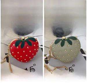 Vue détaillée des sacs fraise en forme de cœur avec rivets et bandoulières dorées