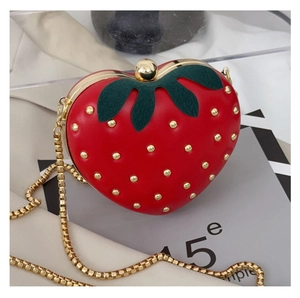 Détail du sac fraise en cœur rouge avec rivets dorés et bandoulière chaîne élégante