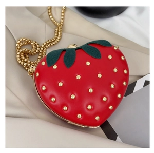 Détail du sac fraise avec des clous dorés et une bandoulière amovible en chaîne dorée