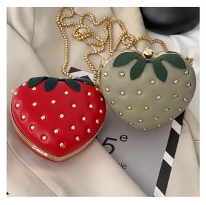 Détail du sac fraise avec des clous métalliques dorés et des détails de feuilles