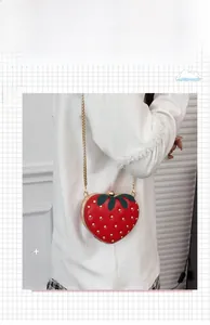Détail du sac fraise rouge avec rivets dorés et bandoulière en chaîne métallique