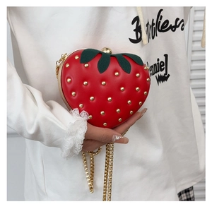 Détail du sac fraise rouge avec rivets dorés et poignée supérieure en forme de feuille