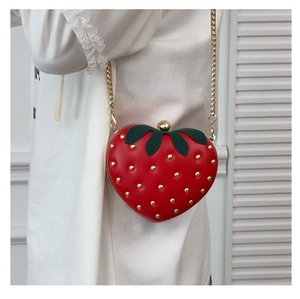 Détail du sac fraise rouge avec décor de feuilles et rivets dorés sur chaîne métal
