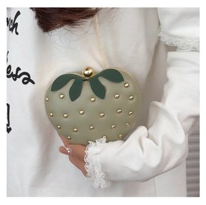 Détail du sac fraise vert avec rivets dorés et fermoir en forme de feuille