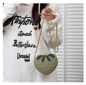 Gros plan sur le sac fraise avec rivets dorés et détails de feuilles vertes