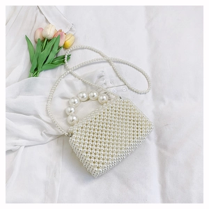 Détail de sac à main en perles tissées avec anse élégante et bandoulière longue chaîne