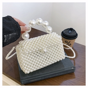 Détail d'un sac à main en perles blanches tressées avec grande poignée et bandoulière