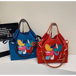 Detail of nylon tote bags with colorful fruit embroidery and woven rope handles