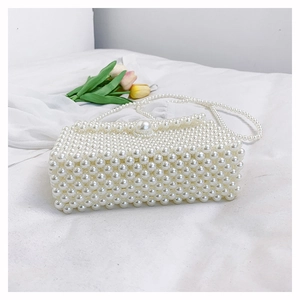 Détail d'un sac à main en perles blanches tressées avec rabat et bandoulière