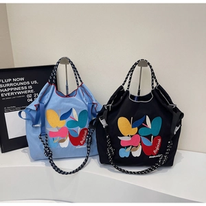 Detail of colorful apple embroidery and black-and-white polka dot straps on tote bags
