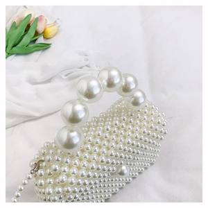 Détail du sac à main en perles blanches avec grande poignée et chaîne en métal