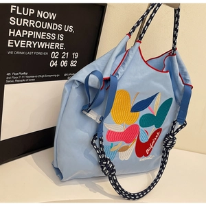 Detail of colorful fruit embroidery and braided rope handles on blue nylon tote bag