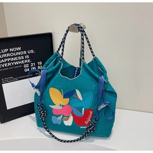 Detail of colorful embroidered apple patterns on tiffany blue canvas tote bag