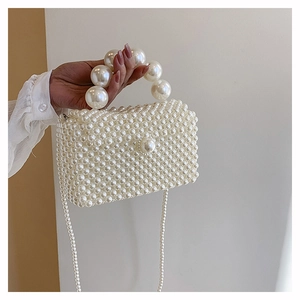 Détail du sac à main en perles blanches avec grande poignée et texture tissée élégante