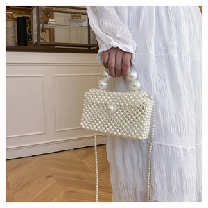 Détail d'un sac à main en perles blanches montrant la texture tressée et la poignée ronde
