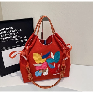 Close-up of red canvas tote bag featuring dense fruit embroidery and rope handle