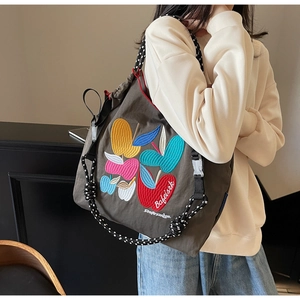 Detailed close-up of colorful apple embroidery on a brown canvas shoulder bag