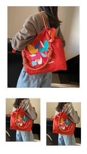 Detail of colorful embroidery and braided strap on a red canvas shoulder bag