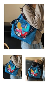 Detail of colorful embroidery and woven rope handle on a dark blue canvas tote bag
