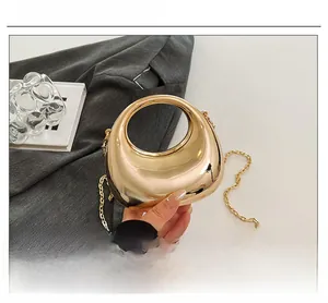 Macro shot of mirror-finish gold dumpling bag with fine chain and hollow metal design
