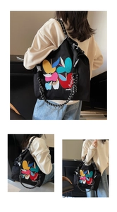 Detail of black canvas tote bag with colorful apple embroidery and woven rope handle