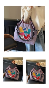 Close-up of purple canvas tote bag with vibrant leaf embroidery and braided blue rope straps