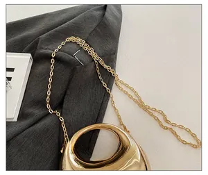 Detailed close-up of polished gold acrylic dumpling bag featuring a sleek chain strap