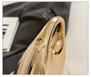Macro detail of high-shine gold mirror bag hardware with sleek chain and lobster clasp