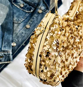 Close-up of champagne gold sequin evening clutch with metal handle and spherical clasp