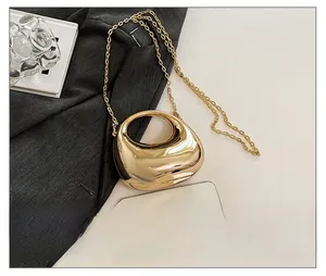 Size comparison of a gold metallic dumpling bag next to a smartphone with a chain