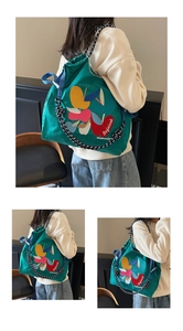 Close-up of colorful fruit embroidery and woven rope straps on a green canvas tote