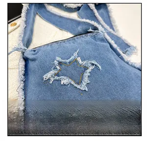 Détail du sac à bandoulière en jean bleu avec un patch étoile effiloché et fermeture éclair noire