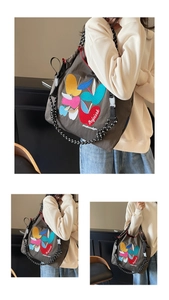 Detail of embroidered apple patches and polka dot strap on a taupe canvas tote bag