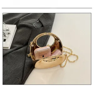 Detail view of mini gold acrylic clutch bag showing internal capacity for cosmetics