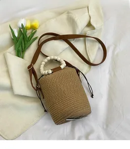 Detail view of woven straw bucket bag with wooden bead handle and drawstring closure