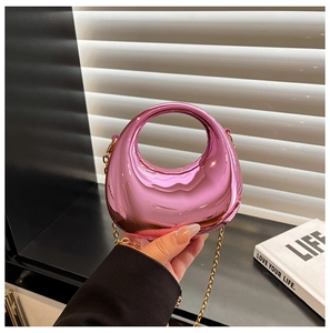 Macro detail of metallic pink acrylic dumpling bag with integrated handle and gold chain