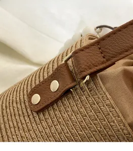 Close-up of golden hardware buckle on beige woven bag with premium brown leather trim