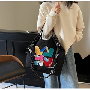 Detail of colorful apple embroidery on black nylon tote with polka dot woven shoulder strap
