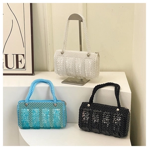 Detailed view of handmade sequined cylinder bags with pearl handles in white, blue and black