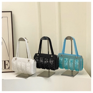 Close-up of beaded mini pillow bags in white, black and blue hanging on a metal rack