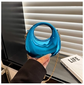 Macro view of blue acrylic mirror bag with gold chain and circular handle detail