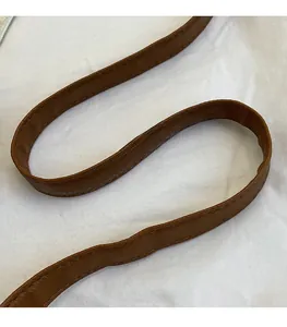 Close-up of brown synthetic leather shoulder strap with visible stitching for bucket bag