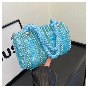 Close-up of light blue sequined cylinder bag featuring pearl details and woven handle
