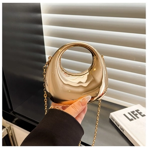 Close-up of golden acrylic dumpling bag with metal chain and circular ring handle